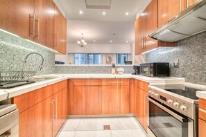 A modern kitchen with wooden cabinets, a stainless steel range, and a tiled backsplash. - Modern Elegance w/ a New York Edge DIFC Apt (Dubai)