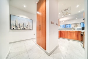 A modern kitchen with wooden cabinets, a tiled floor, and a cityscape painting on the wall.