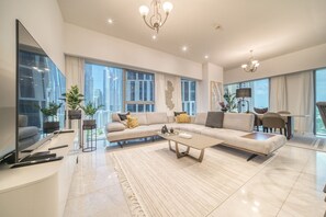 Una sala de estar moderna con un sofá modular grande, un televisor de pantalla plana y una zona de comedor con mesa y sillas.