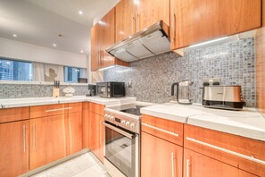 Une cuisine moderne avec des meubles en bois, une cuisinière en acier inoxydable et un dosseret carrelé.