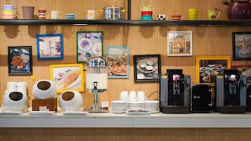Una barra de cafetería con varias máquinas de café, una selección de tazas y vasos, y cuadros en la pared.
