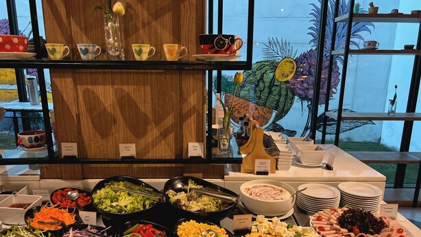 Un bufé con diversas opciones de comida, como ensaladas, quesos y carnes.