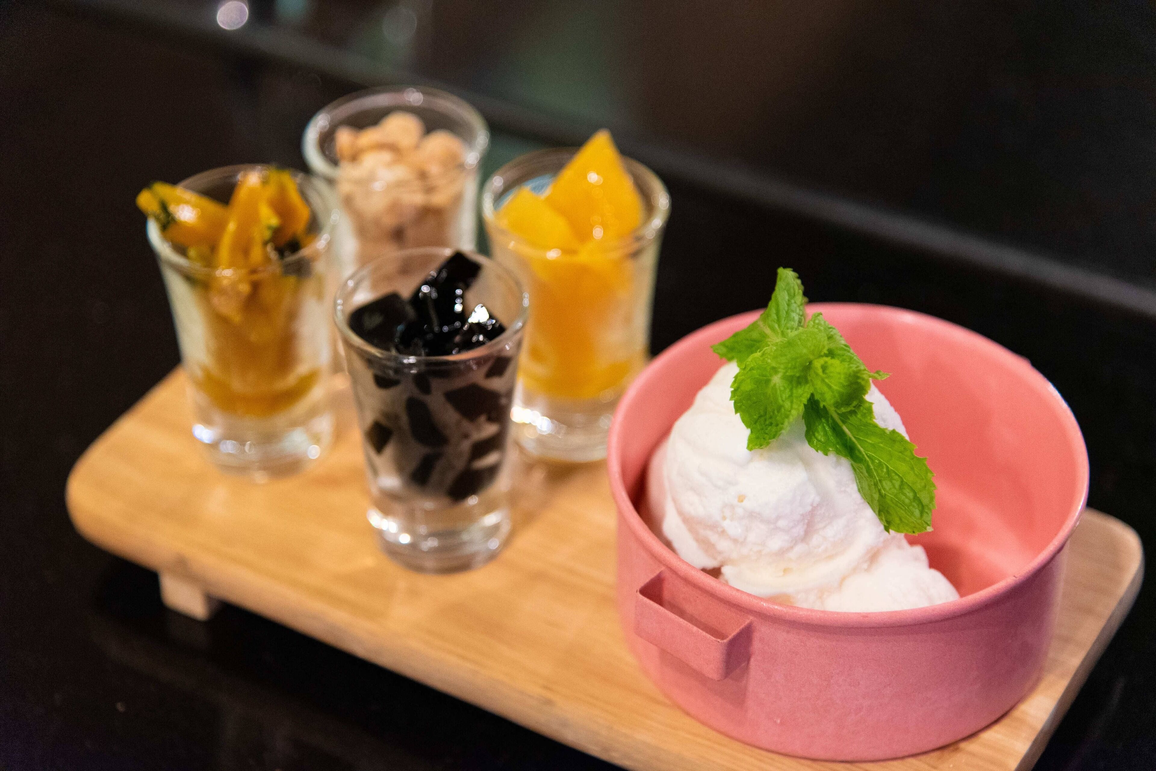 A dessert tray with various ice cream and fruit options on a wooden board.