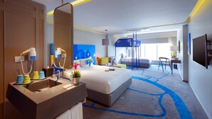 Una habitación de hotel moderna con una cama grande, tocador empotrado y un espejo amplio.