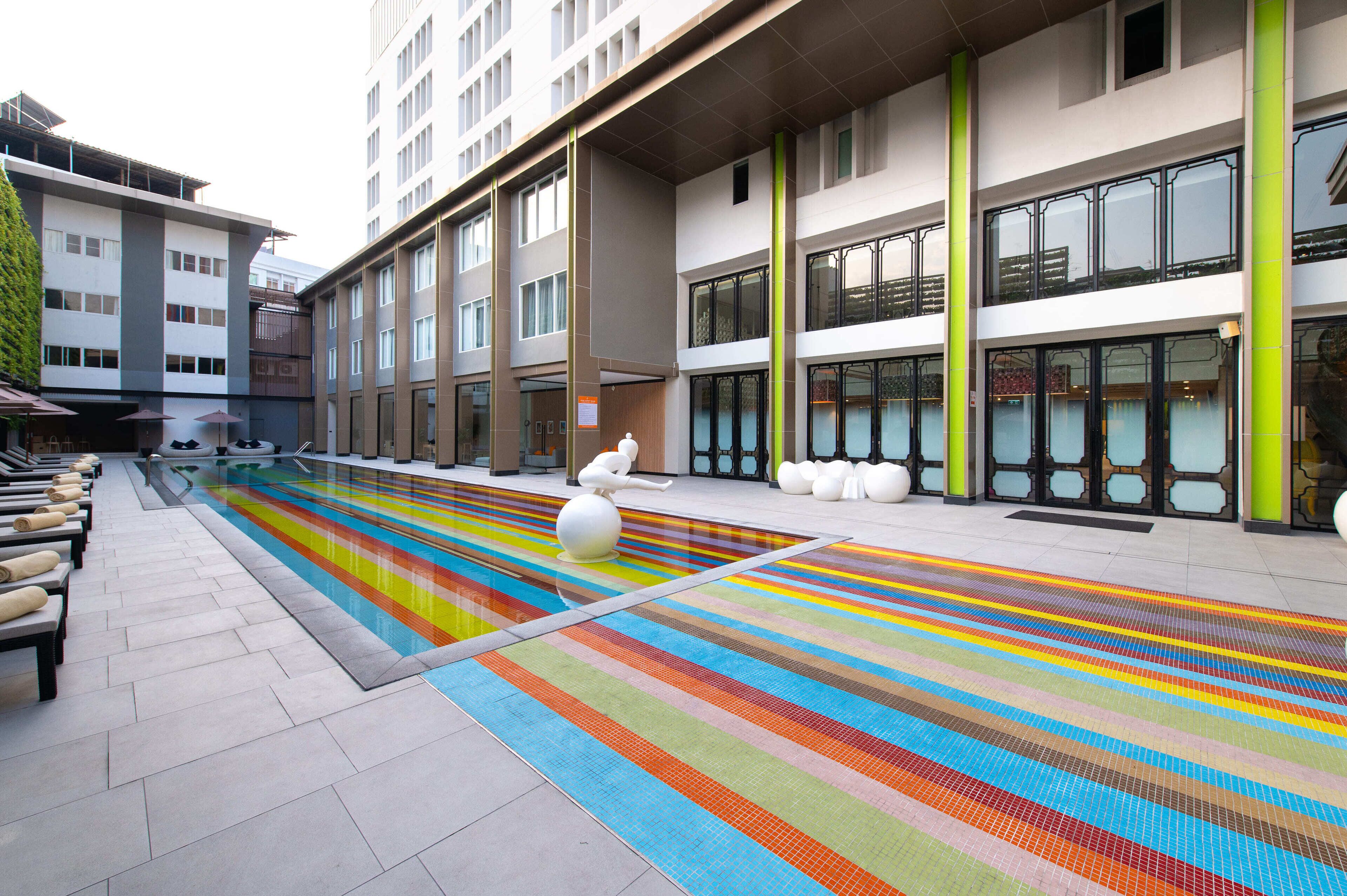 A modern building with a pool area featuring colorful tiles and a statue.