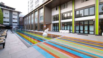A modern building with a pool area featuring colorful tiles and a statue.