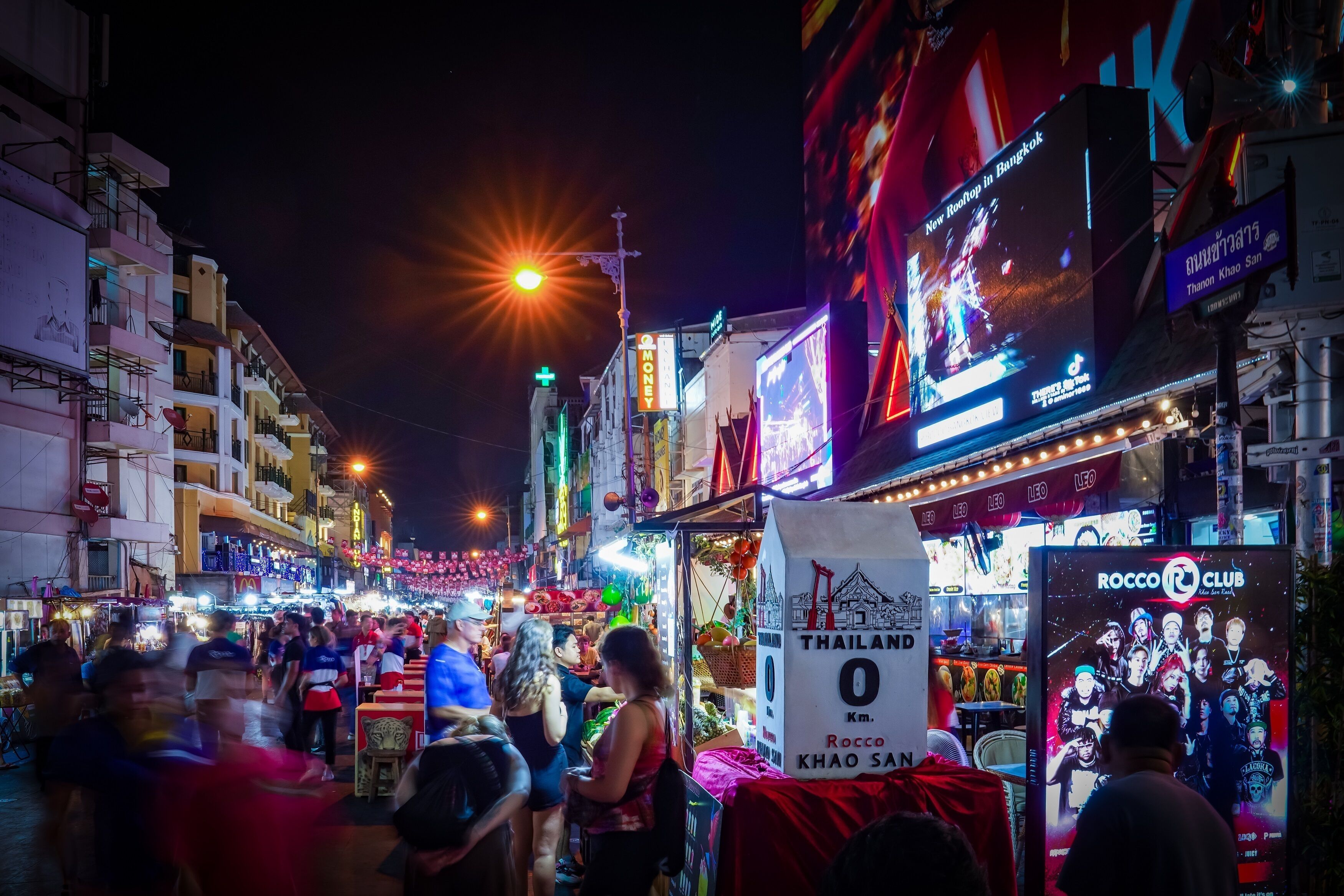 Una calle concurrida de noche, con letreros iluminados y mucha gente.