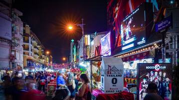 Una calle concurrida de noche, con letreros iluminados y mucha gente.