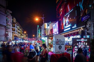 Μια πολυσύχναστη οδός τη νύχτα, με φωτεινές επιγραφές και πλήθος κόσμου.