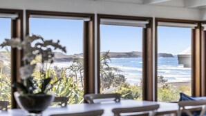 A dining area with a view of the ocean and hills. - Victoria's - Hamptons Charm, Pool, Pizza Oven, Spectacular Ocean Views (Emerald Beach)