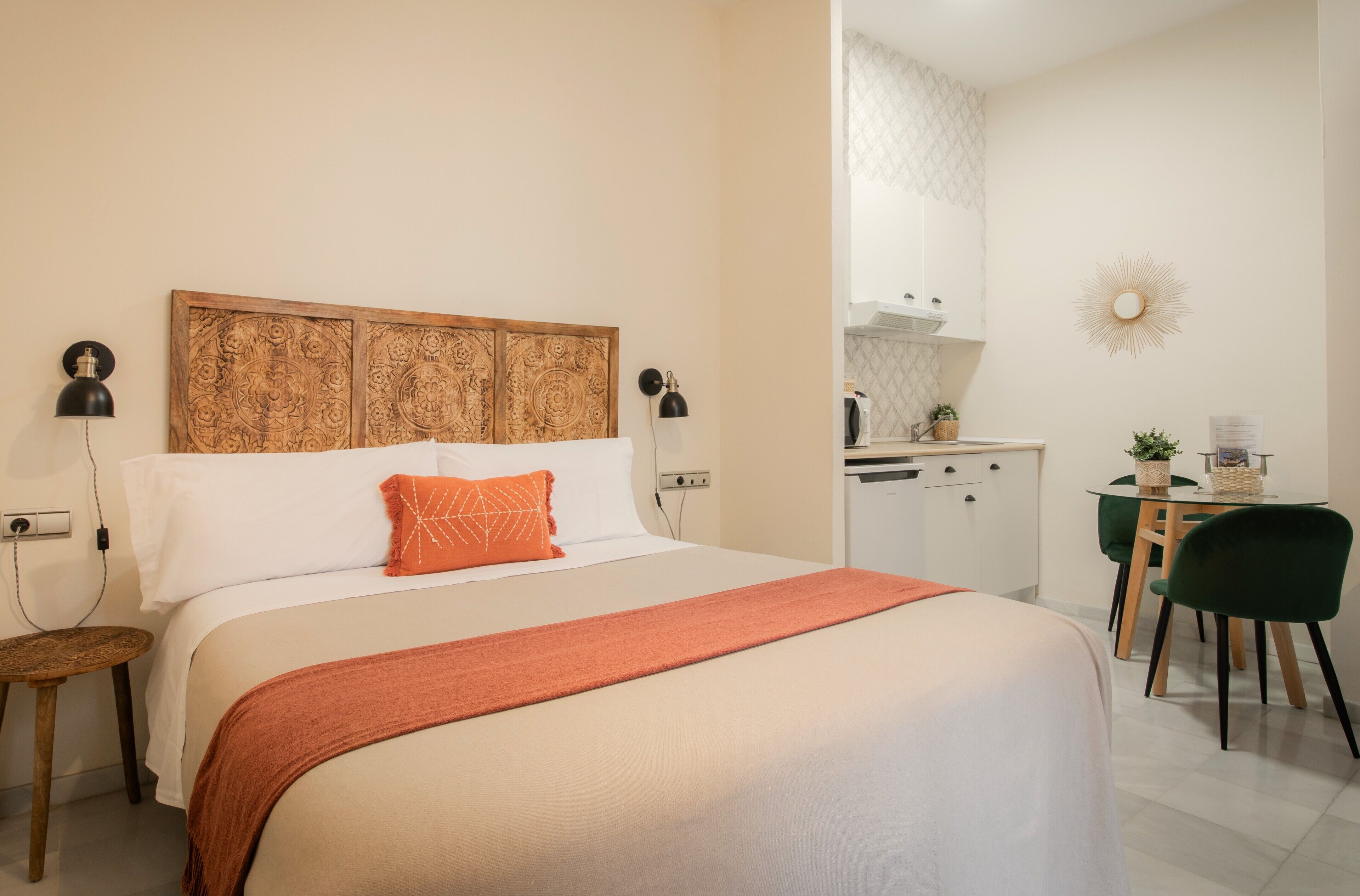 Una habitación de hotel con cama, escritorio, silla y kitchenette.