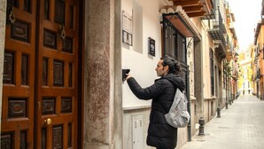 A person standing at a door with a keypad, a narrow street with buildings, and a fire hydrant on the sidewalk. - APARTAMENTOS VITA CENTER  (Granada)