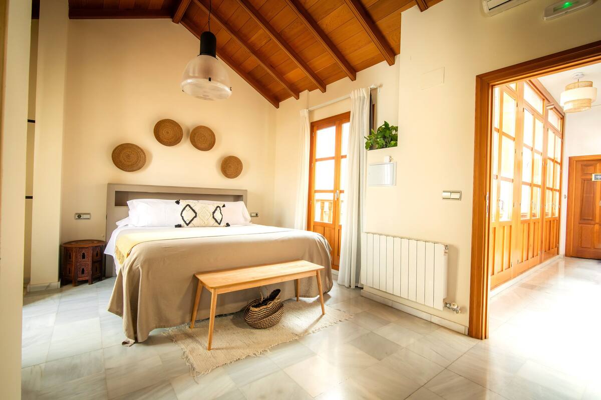 A bedroom with a bed, wooden bench, bedside table, and a wall-mounted plant.