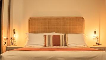 Una cama bien hecha con un cojín a rayas, un cabecero de madera y lámparas de noche.