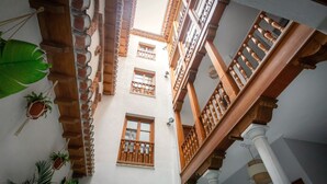 A courtyard with a wooden balcony, columns, and hanging plants. - APARTAMENTOS VITA CENTER  (Granada)