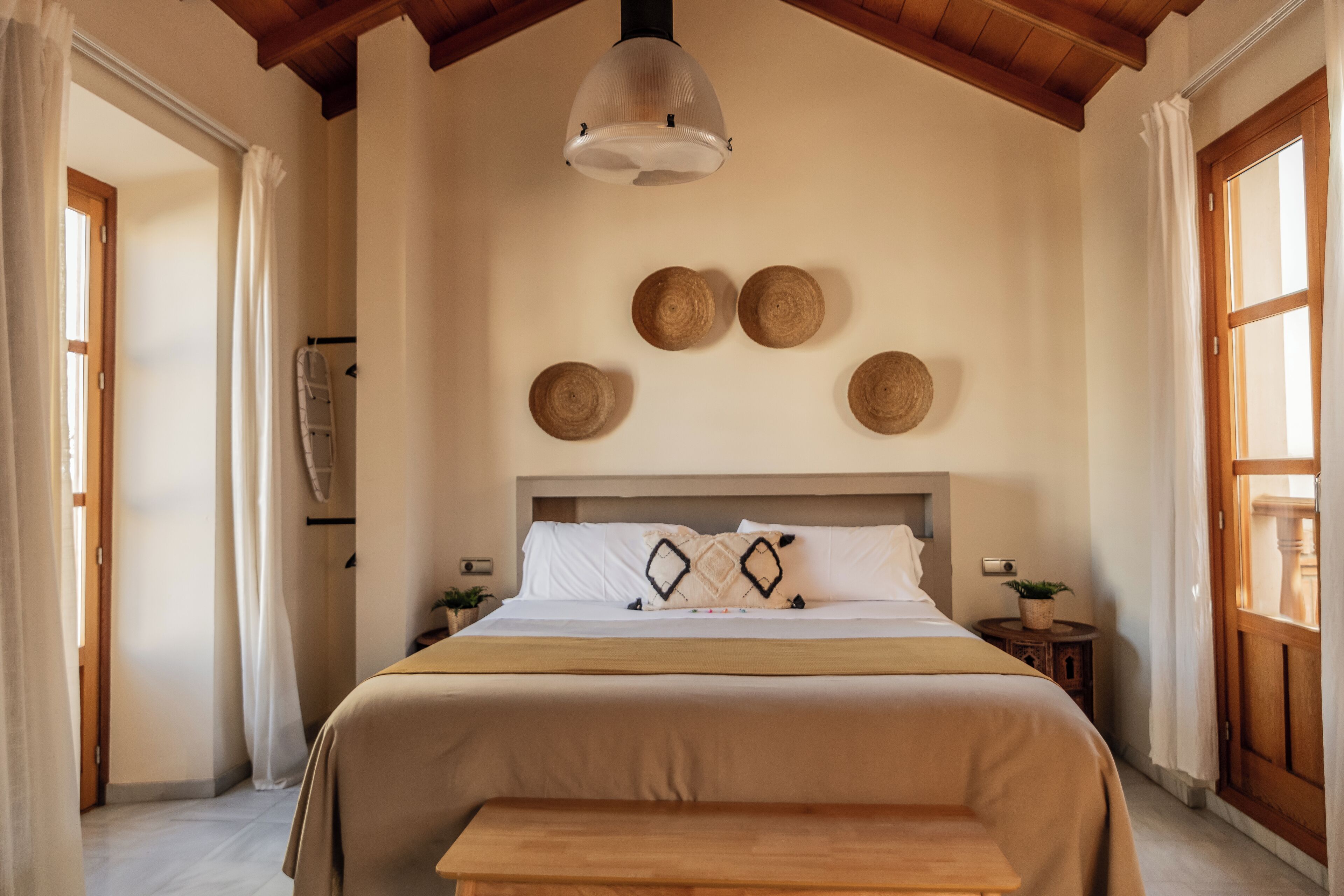Ein Schlafzimmer mit einem großen Bett, einem Holz-Kopfteil und einer Deckenleuchte.