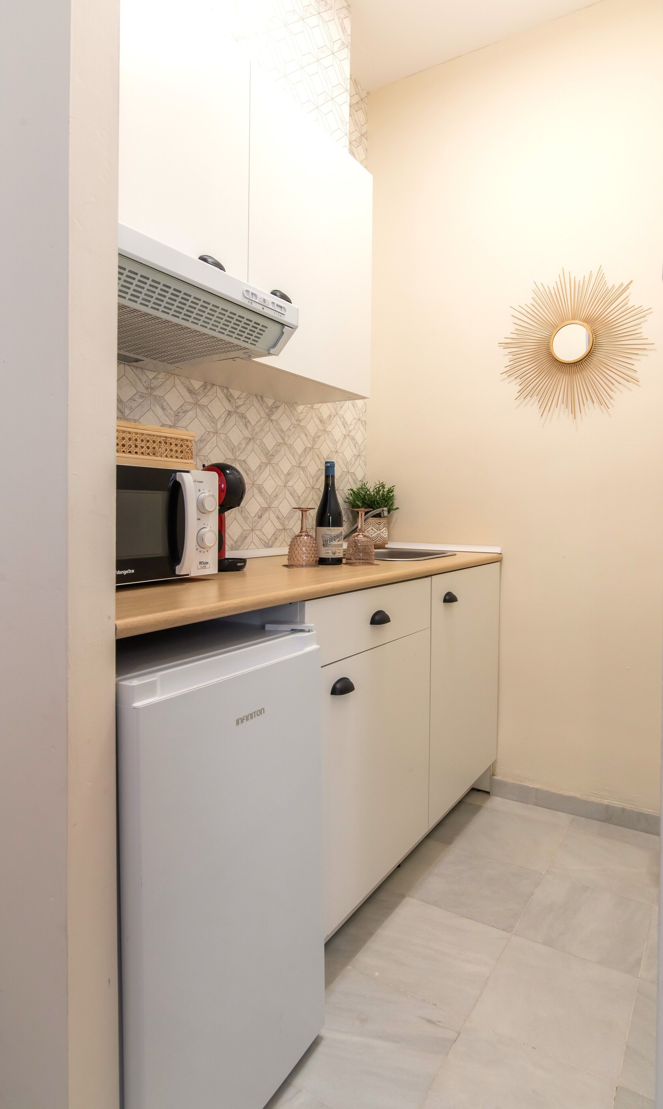 A compact kitchen with a microwave, a small refrigerator, and a sink.