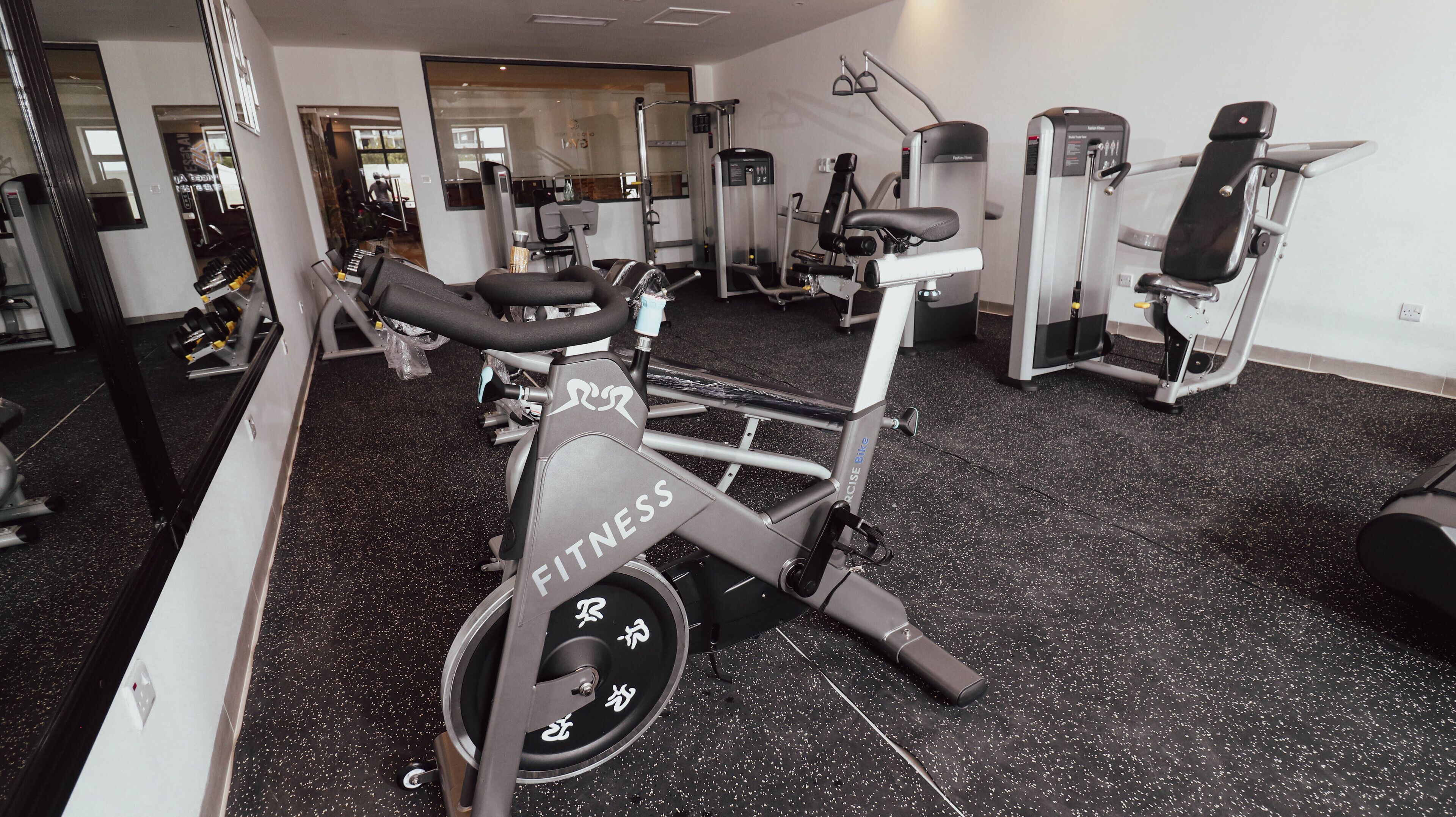 Une salle de sport équipée de vélos d’exercice, d’appareils de musculation et d’un mur recouvert de miroirs.
