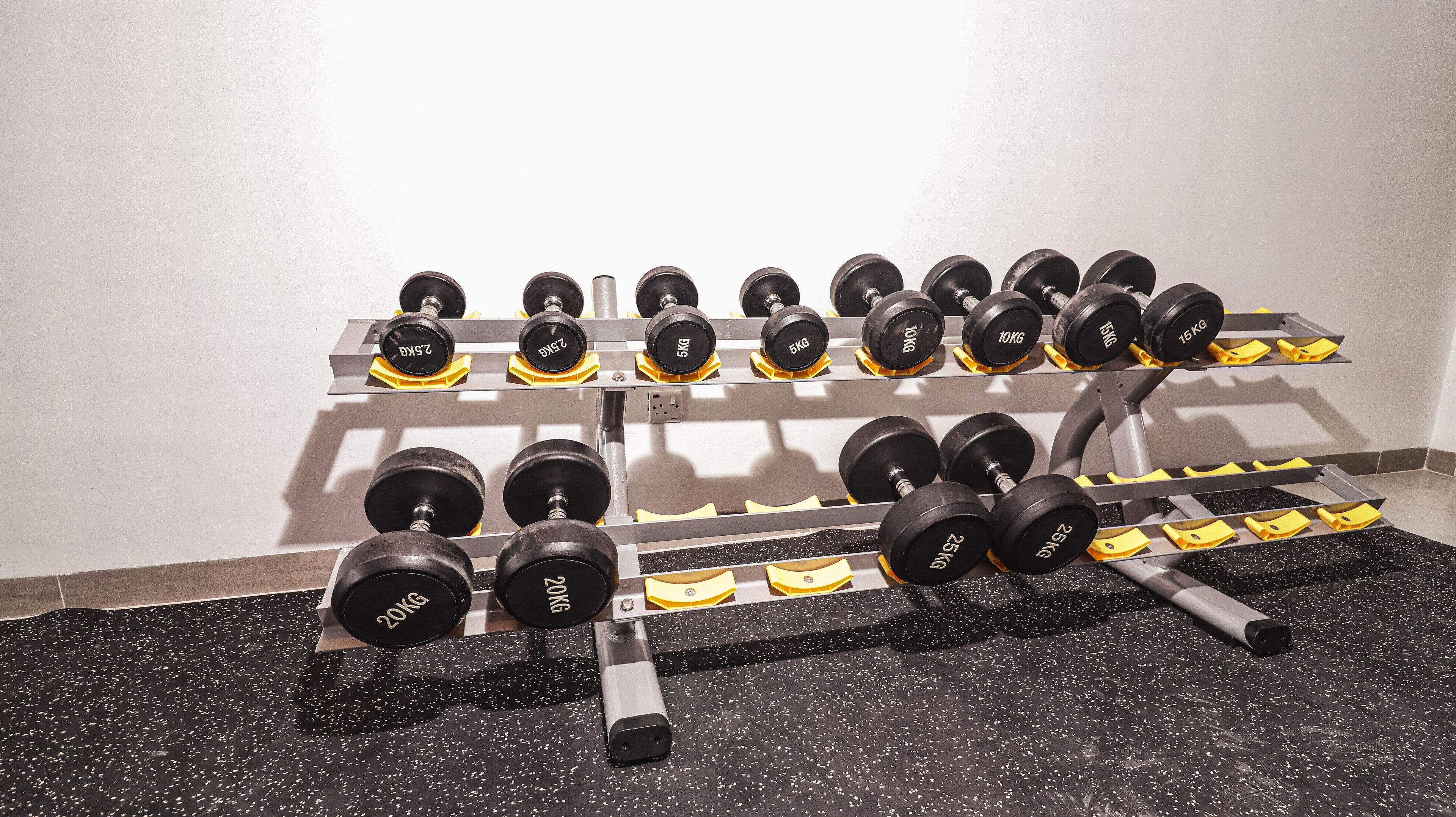 Ein Fitnessraum mit verschiedenen Kurzhanteln, die in Regalen angeordnet sind.
