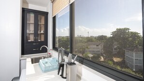 Een moderne keuken met een groot raam, een zwart kastje en een blauwe afwasslede.
