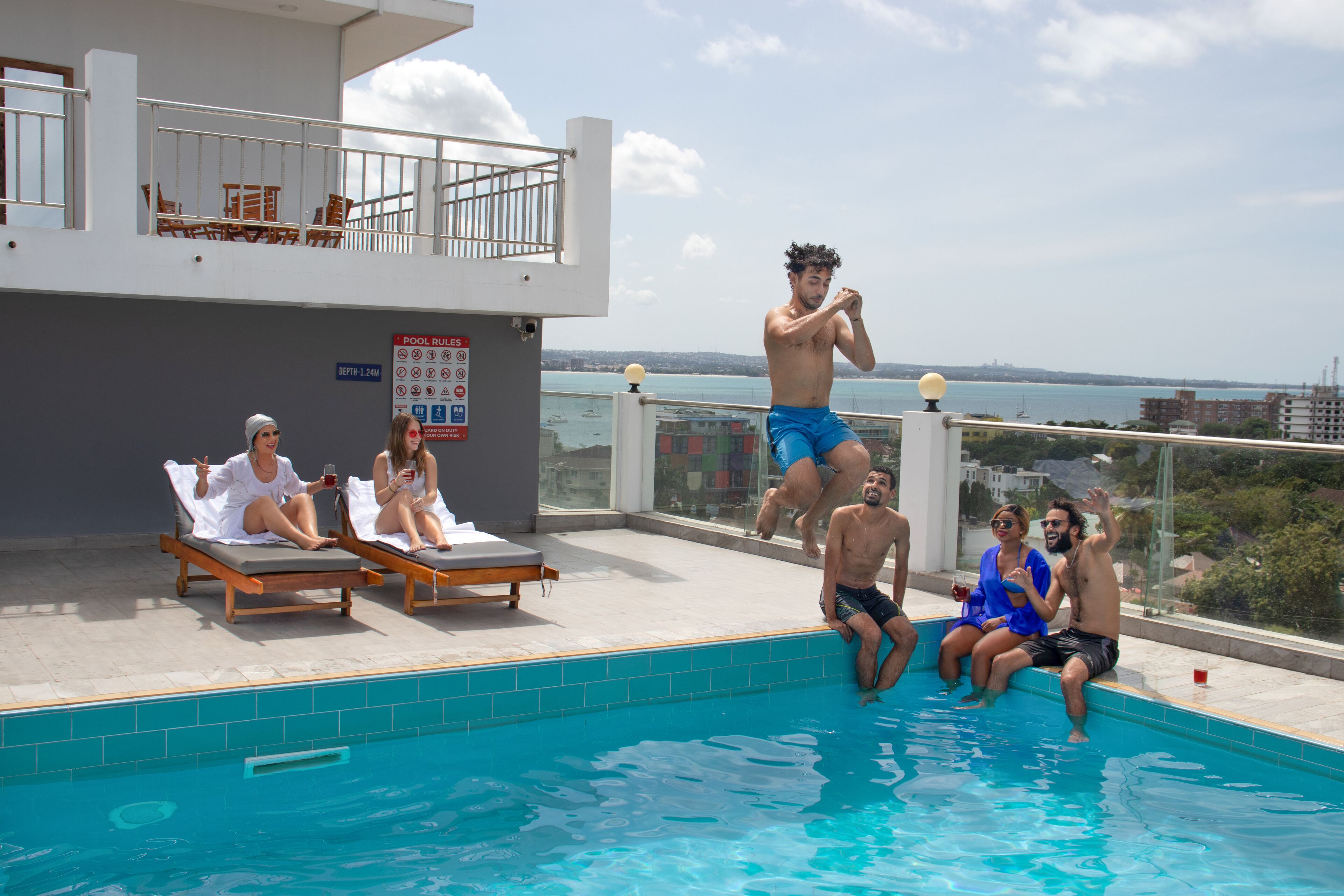 A rooftop pool area with lounge chairs, a pool, and a view of the city skyline.