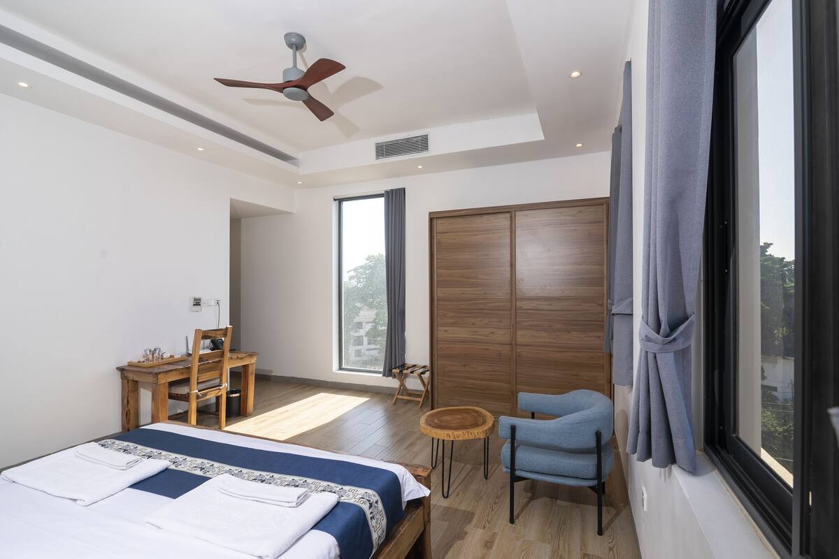 Een moderne hotelkamer met een bed, een bureau, een stoel, een klein tafeltje en een kledingkast.