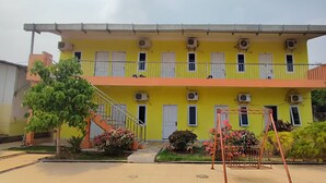 A two-story building with a yellow facade, multiple windows, and air conditioning units. - Hotel O Garuda Bandara Guesthouse (Palembang)