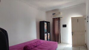 A bedroom with a bed, a wardrobe, a door, and an air conditioning unit. - Hotel O Garuda Bandara Guesthouse (Palembang)