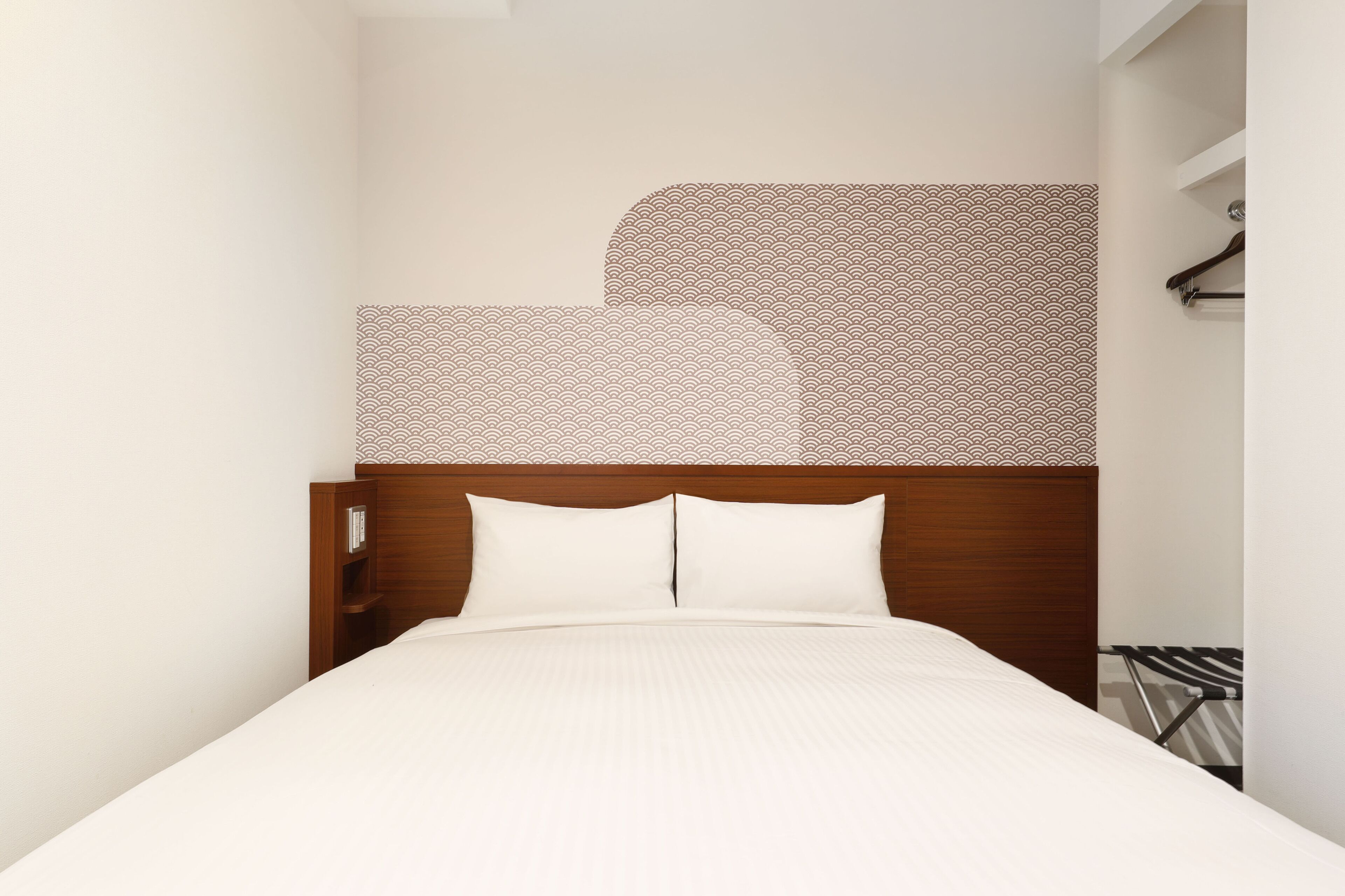 A neatly made bed with a wooden headboard and white bedding in a hotel room.