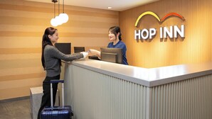 A reception desk at a hotel with a wooden wall and a sign that reads "HOP INN". - Hop Inn Kyoto Shijo Omiya (Kyoto)