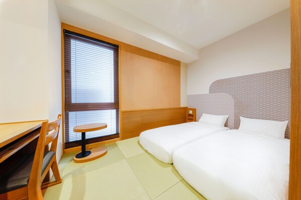 Una habitación de hotel con cama, escritorio y ventana con persianas.