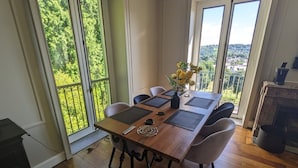A dining area with a wooden table, four chairs, and a vase with flowers.