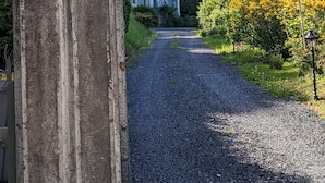 A gravel path leading to Villa Morton, surrounded by lush greenery and trees.