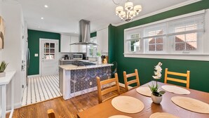 Une cuisine moderne dotée d’un îlot central, de meubles blancs et d’un mur d’accent vert.