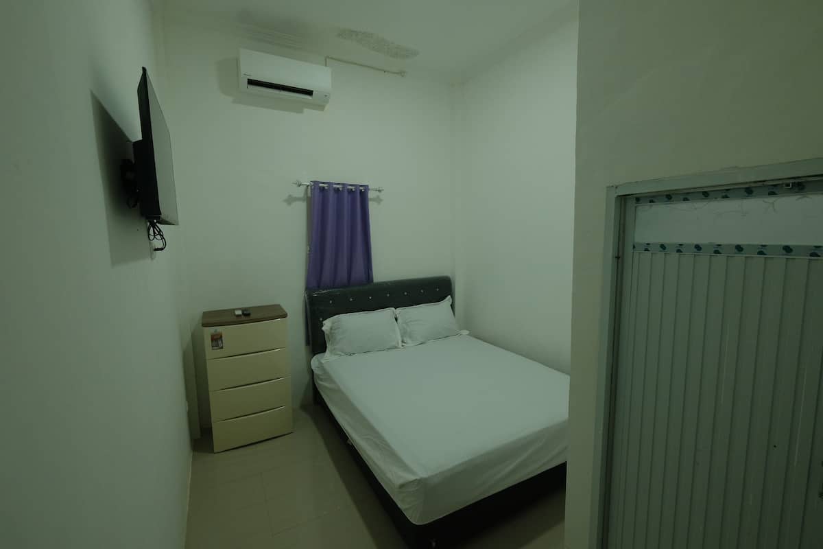 Un dormitorio con cama, cómoda, televisor montado en la pared y aire acondicionado.