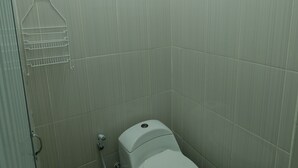 A small, narrow bathroom with a toilet, a shower area, and a towel rack. - Hotel O Penginapan Permata Hijau Syariah Near Bukit Teletubbies (Parepare)