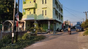 A multi-story building with a green facade, a gated entrance, and a small shop on the ground floor. - Hotel O Penginapan Permata Hijau Syariah Near Bukit Teletubbies (Parepare)