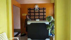 A reception desk with a clock, a sign indicating the location, and a potted plant. - Hotel O Penginapan Permata Hijau Syariah Near Bukit Teletubbies (Parepare)