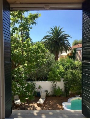 A backyard with a pool, a palm tree, and a chair. - Maison Proche Gare et Centre, Parkings et Piscine (Avignon)
