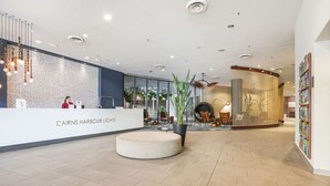 Un hall d’hôtel comprenant un comptoir d’accueil, un espace salon et une grande plante en pot.