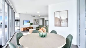 Un salon moderne avec une table ronde, des chaises vertes, un canapé et un téléviseur.