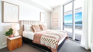 Une chambre moderne avec un grand lit, une vue sur l’extérieur et un balcon.