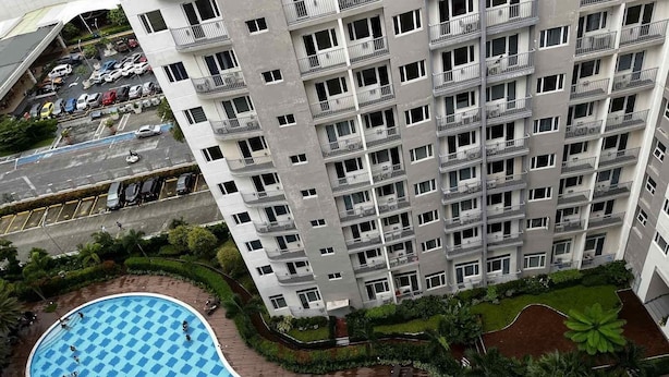 A high-rise residential building with a pool area featuring a checkered pattern. - Lovely 1BR Condo SM Southmall 100mbps Netflix Disney+ (Las Piñas)