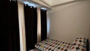A room with a bed, an air conditioning unit, and curtains. - Lovely 1BR Condo SM Southmall 100mbps Netflix Disney+ (Las Piñas)