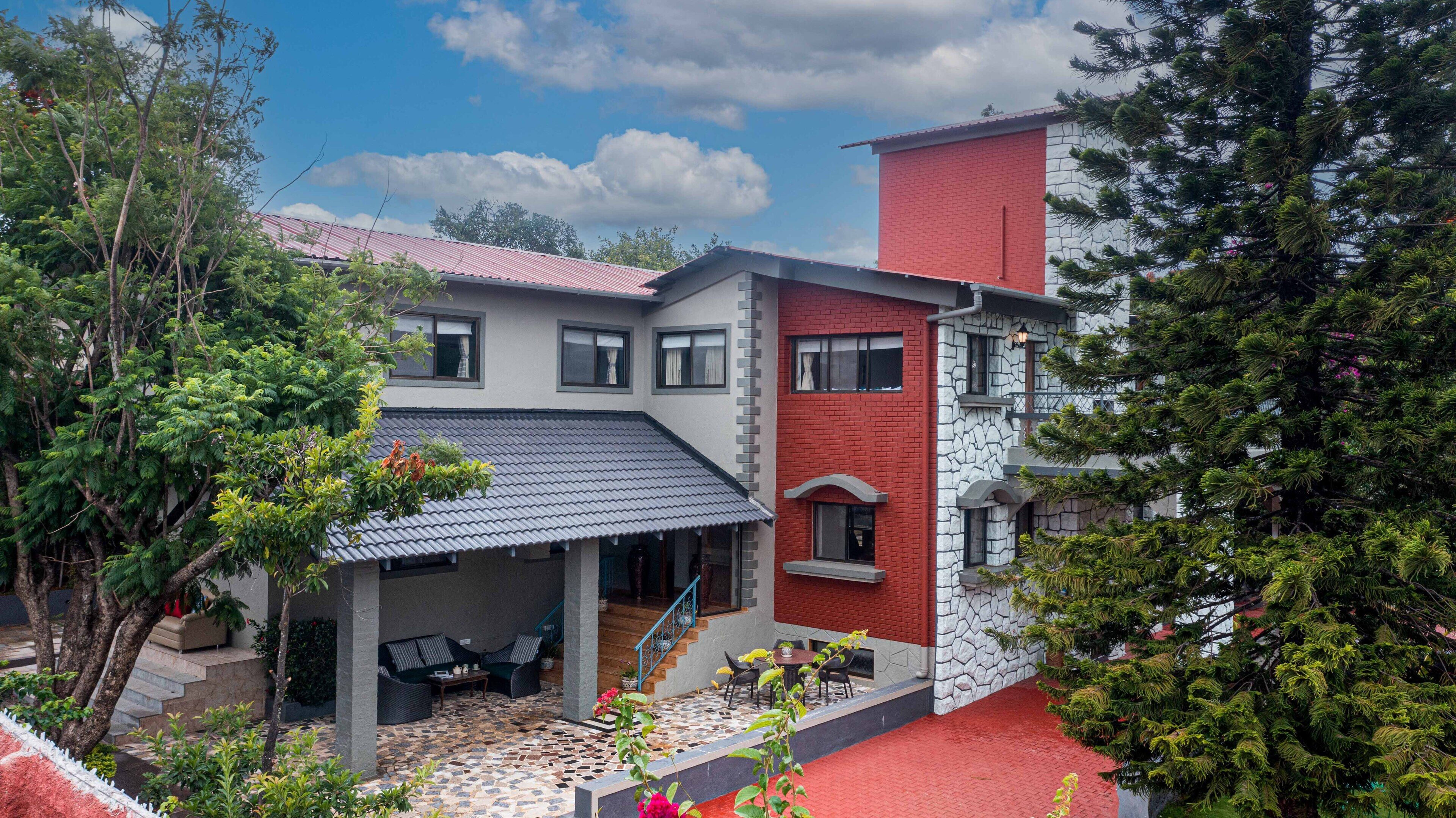A two-story house with a covered patio area featuring outdoor furniture and a tiled floor.
