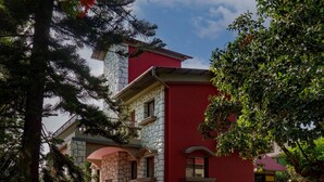 Un edificio con fachada de piedra, sección de ladrillo rojo y un camino de ladrillo rojo que lleva a la entrada.