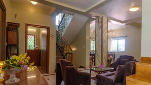 Amplia sala de estar con chimenea de mármol, una escalera y un área de descanso con una mesa de centro de vidrio.
