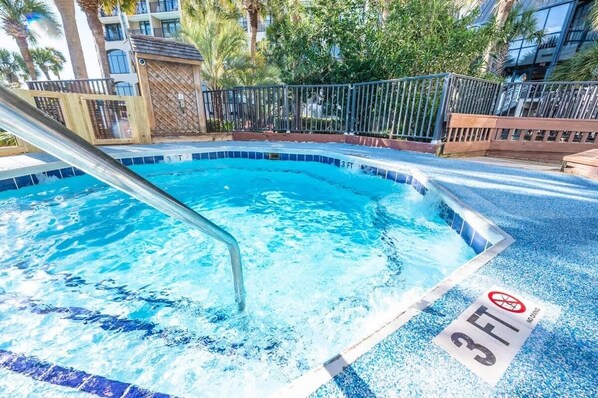 Une piscine dont la profondeur maximale est de 3 pieds, entourée d’une clôture en bois et de palmiers.