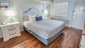 Une chambre à coucher avec un lit, une table de chevet, une commode et une porte.
