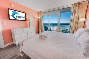 Une chambre d’hôtel avec un grand lit, un téléviseur fixé au mur, une commode et une vue sur l’océan.